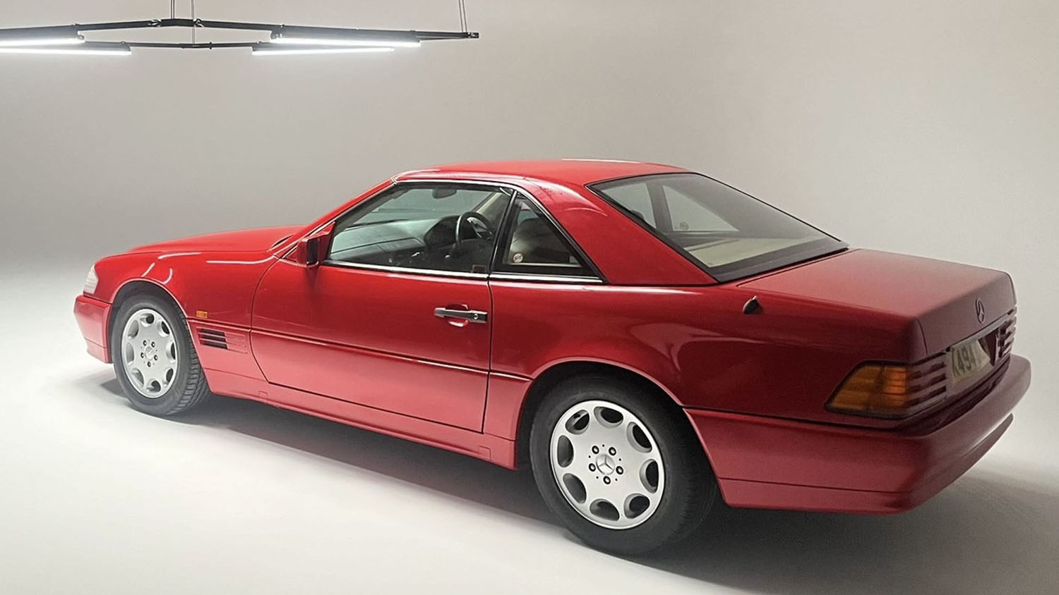 Rear three-quarter view of red Mercedes-Benz SL R129 convertible photographed in studio